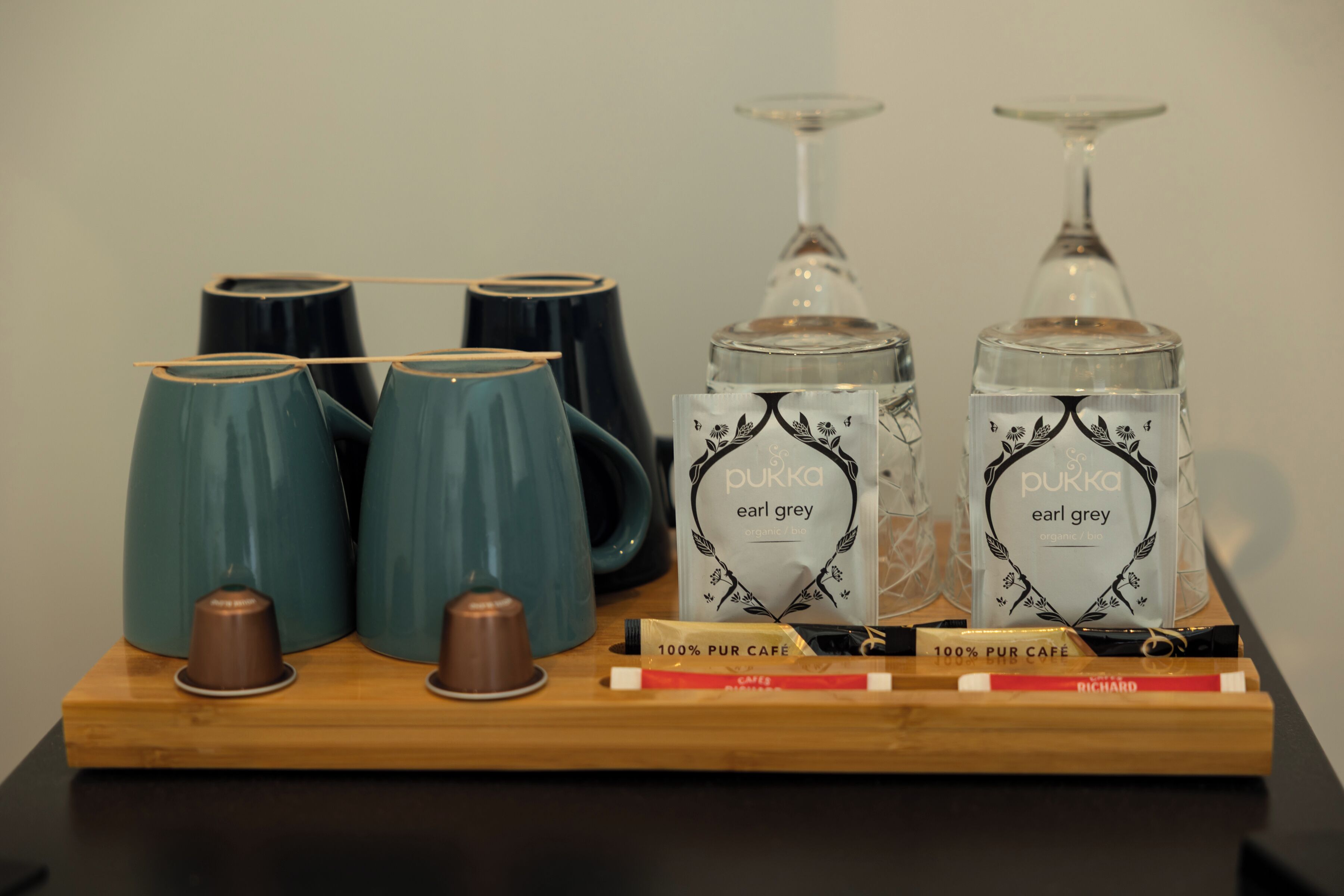 Una exhibición de té Earl Grey Pukka, tazas de té y una bandeja de madera con bolsitas de té.