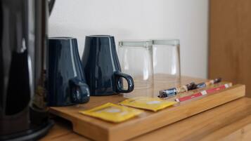 A wooden tray with coffee cups, a glass, and some snacks on a table.