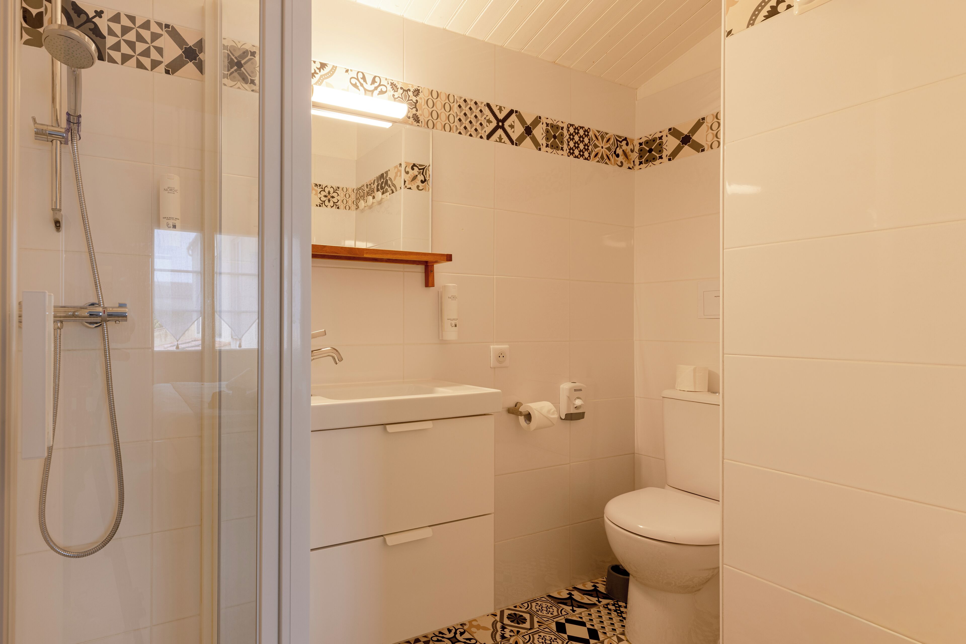 Une salle de bain avec douche, toilettes et lavabo.