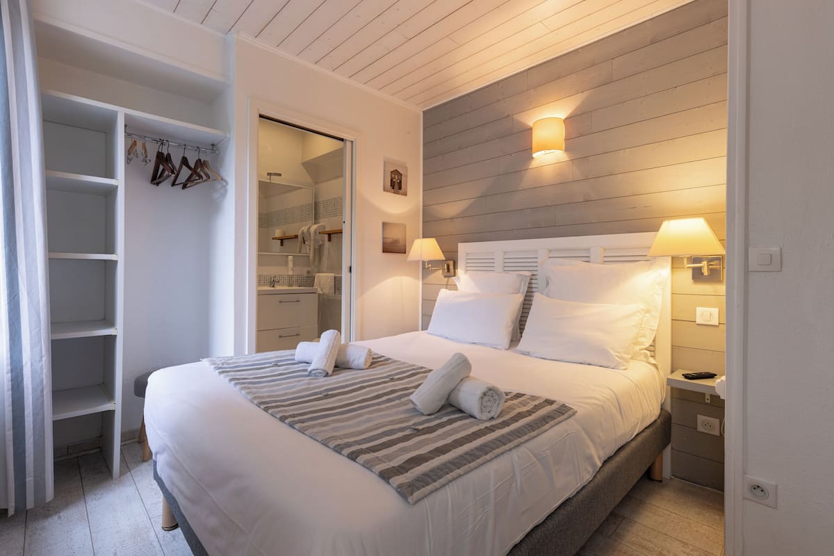 A neatly arranged bedroom with a large bed, a walk-in closet, and a wooden ceiling.