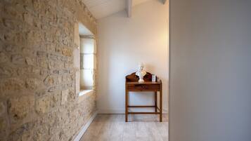 Quarto com parede de pedra, uma escrivaninha de madeira e uma janela.