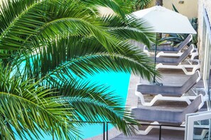 A poolside area with lounge chairs and a palm tree. - Hotel Le Square (Saint-Pierre-d'Oleron)