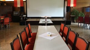 Une salle de conférence équipée d’un grand écran, de chaises rouges, d’une table portant le numéro 5 et d’une horloge au mur.
