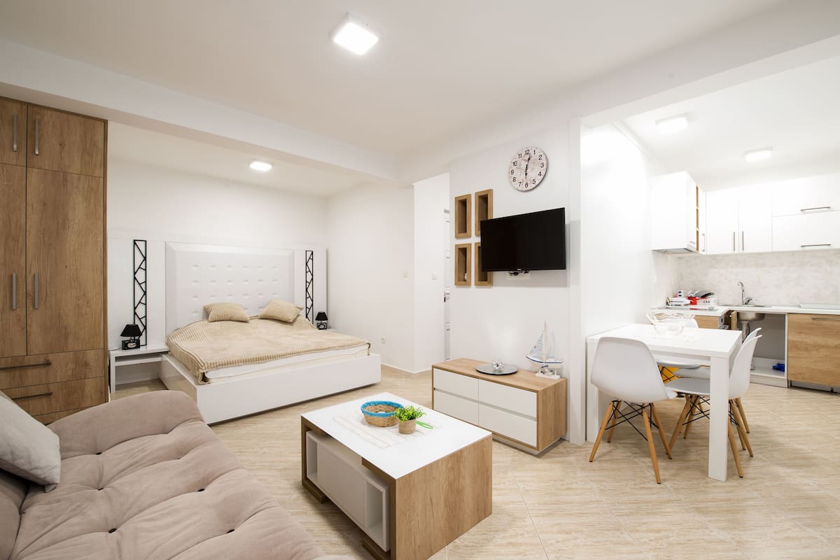 Un dormitorio moderno y bien iluminado con cama, mesita de noche y un escritorio pequeño con silla.