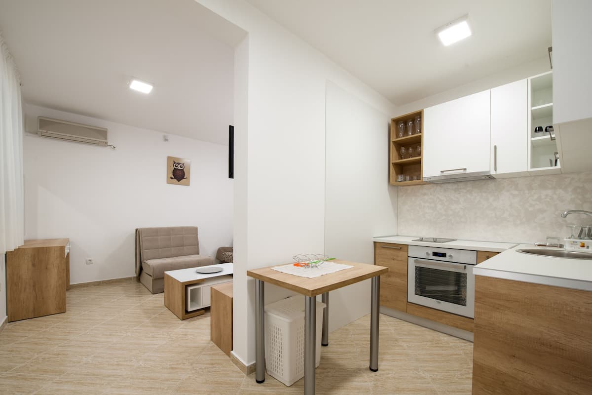 Una cocina moderna con horno empotrado, una mesa de comedor y un sofá en el área de estar contigua.