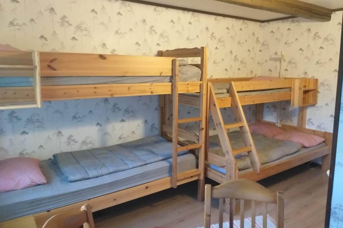 Et soveværelse med køjeseng, stige og stol.