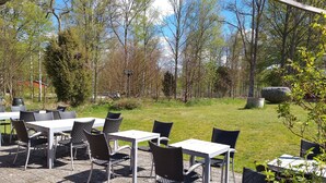 An outdoor patio with tables and chairs, surrounded by trees and a grassy area. - STF Långasjö Vandrarhem (Långasjö)
