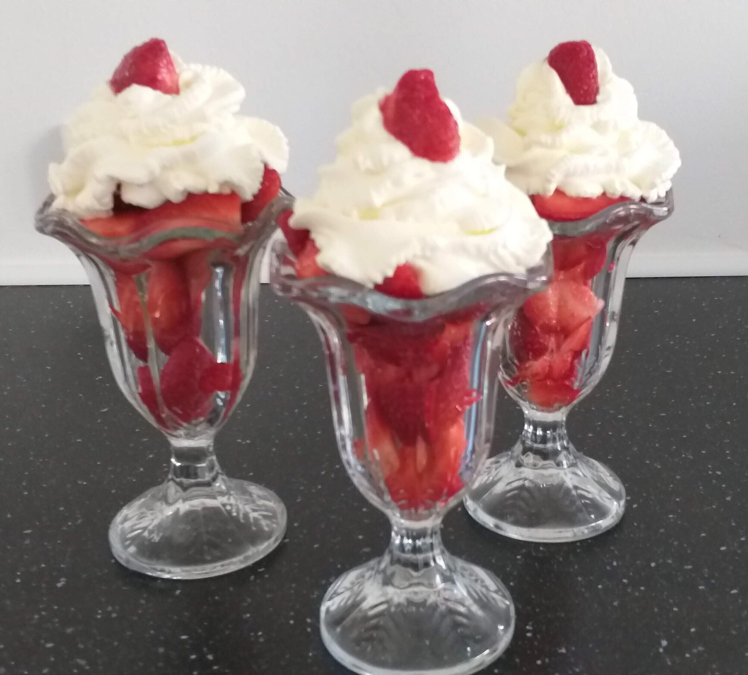 Three dessert cups with whipped cream and strawberries.