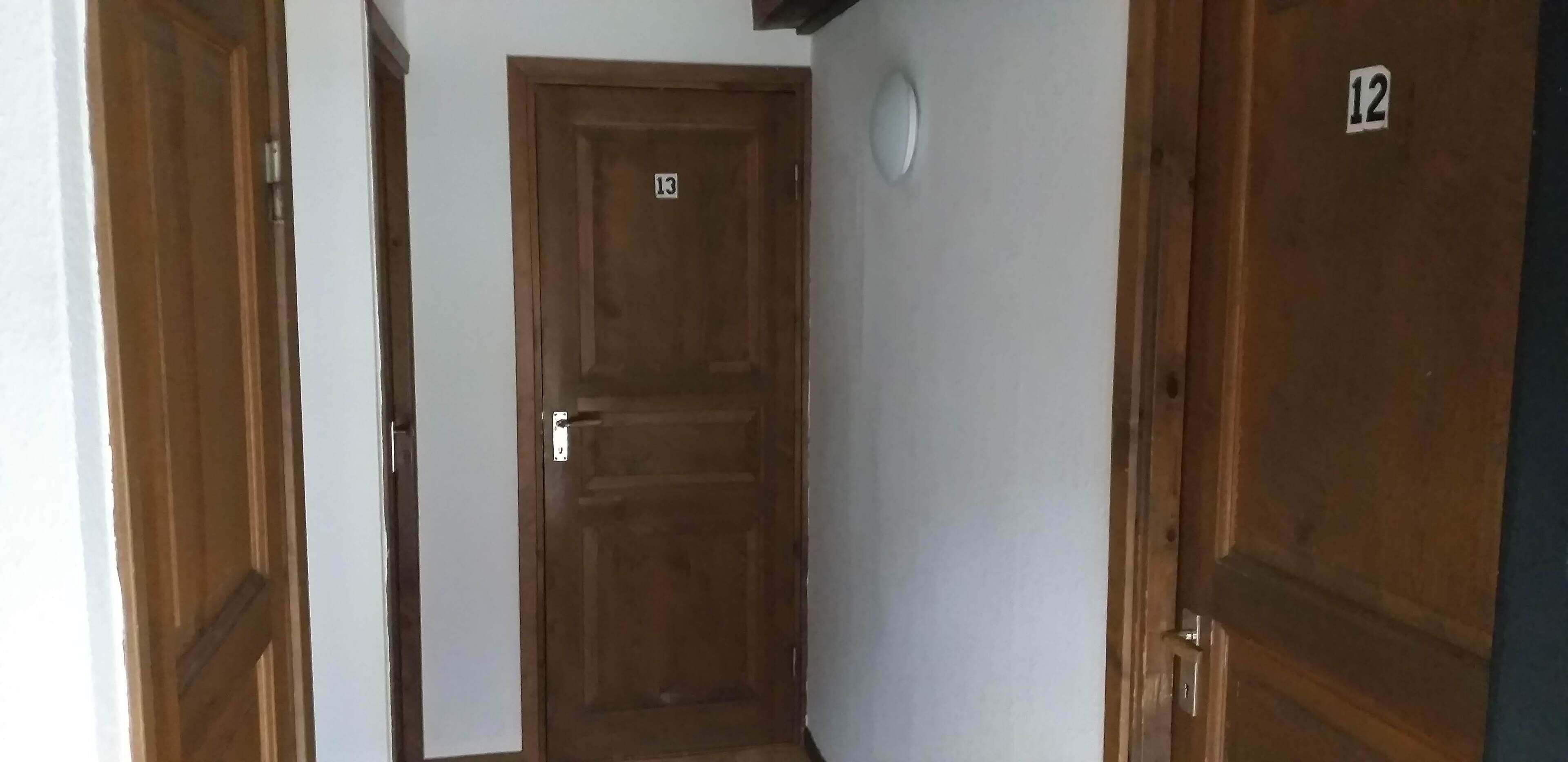 En smal korridor med dörrar av trä, numrerade 12 och 13.