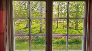 A window with a view of a grassy area and trees. - STF Långasjö Vandrarhem (Långasjö)