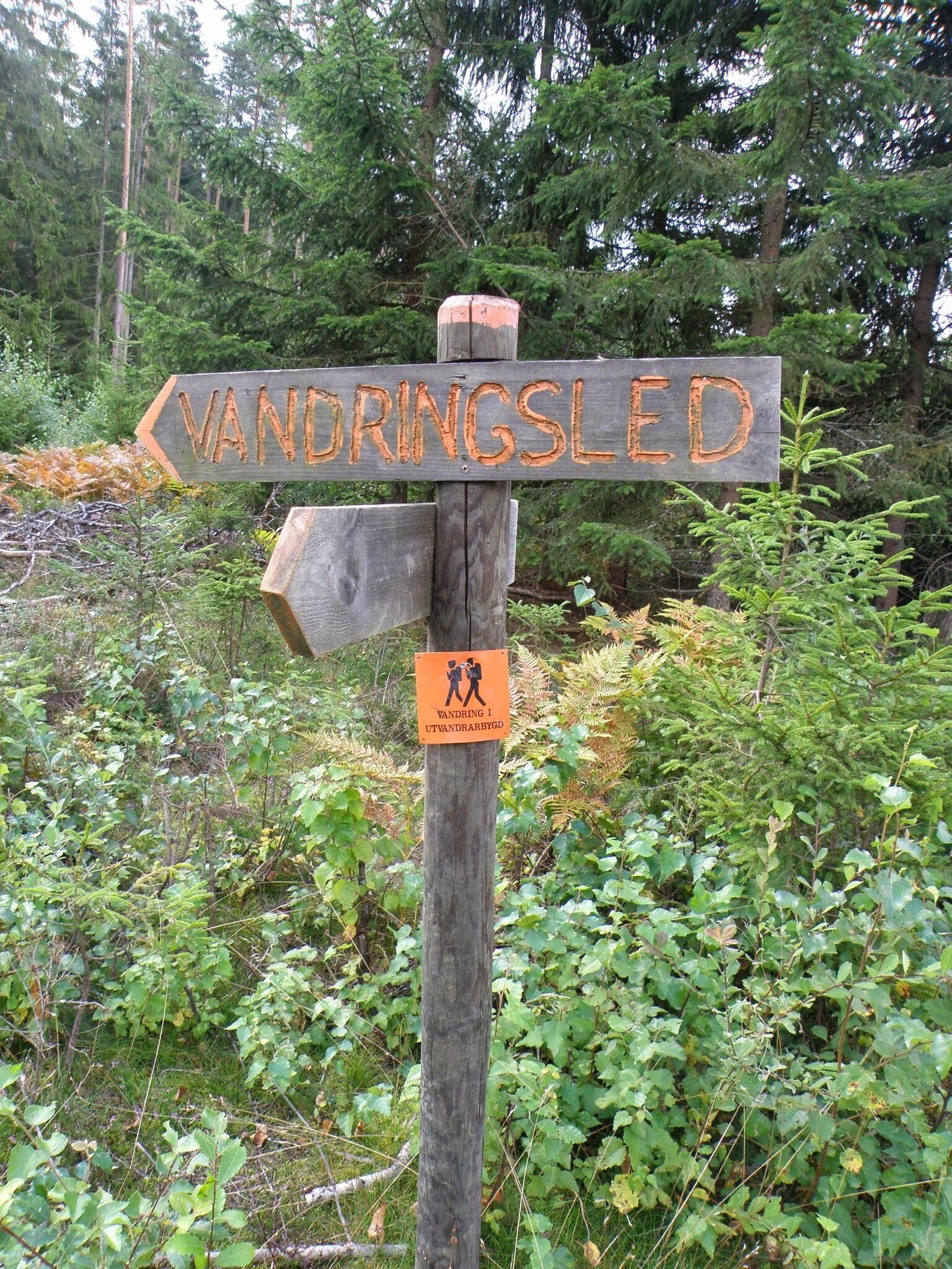 Un panneau indicateur en bois, doté de flèches pointant vers différentes destinations.