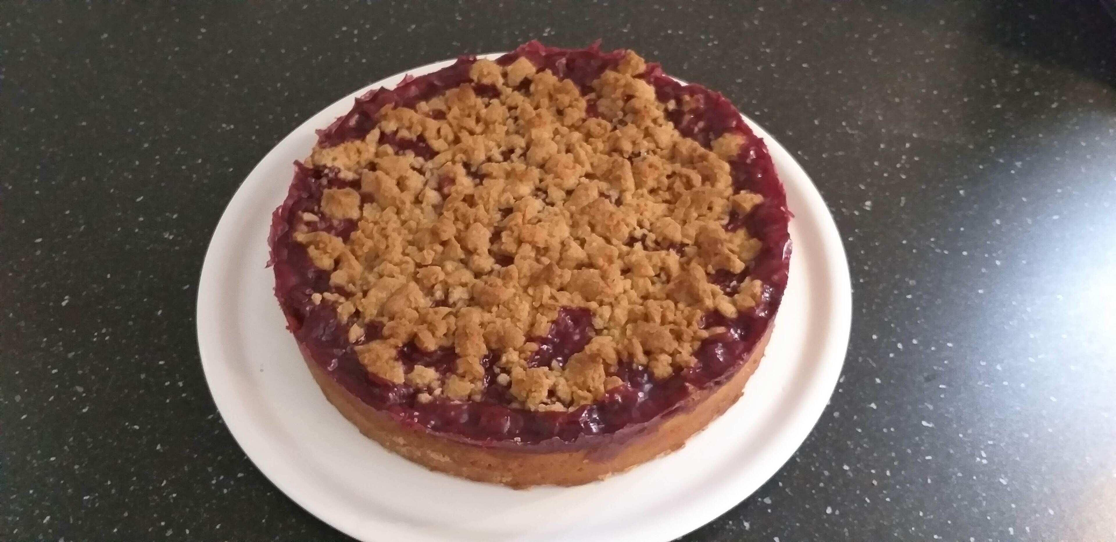 Un postre redondo con cobertura desmenuzable sobre un plato blanco.