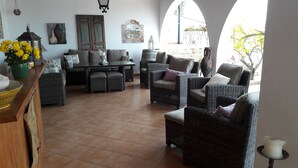 A spacious patio with wicker furniture, a tiled floor, and a view of the outdoors.