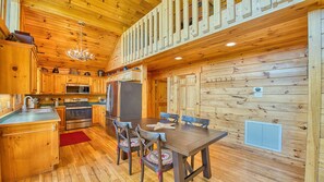 A wooden cabin interior with a kitchen, dining area, and a staircase. - 🏔 Awesome View Cabin – Stunning Views - Hot Tub - Pet Friendly - Game Loft. (Maggie Valley)