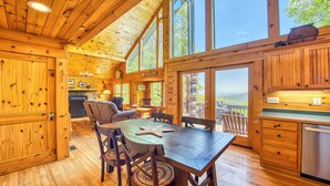 Una cabaña espaciosa con un gran comedor, pisos de madera y vistas a las montañas a través de amplios ventanales.