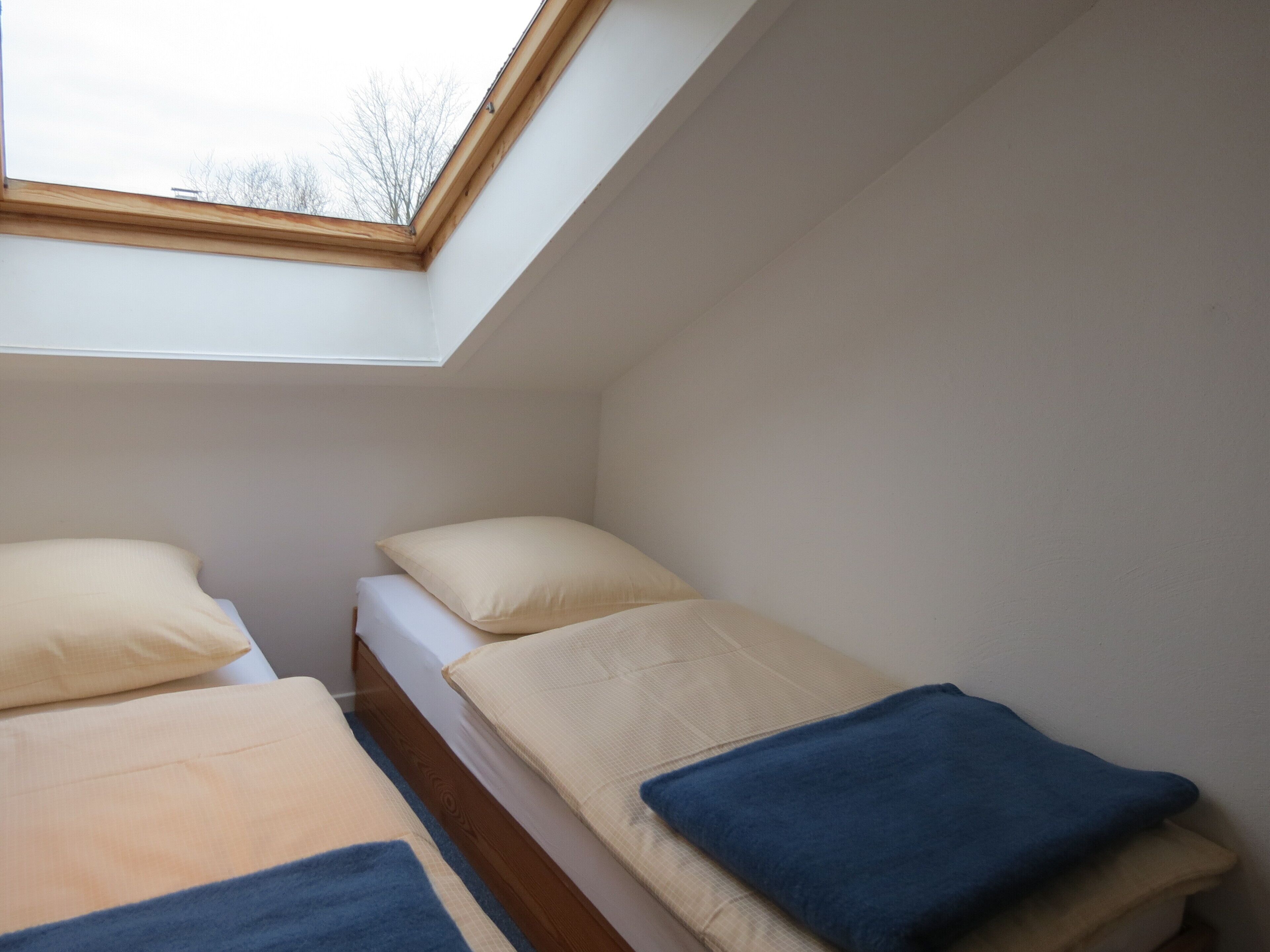 Un petit appartement d’une seule pièce, comprenant deux lits, une lucarne et une vue sur le ciel.