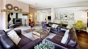 A living room with a fireplace, leather sofas, a coffee table, and a bookshelf.