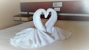 A neatly made bed with a towel arranged in the shape of a swan. - Residencial Sol (Portimão)