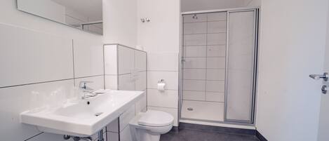 Un baño moderno con lavamanos, inodoro y cabina de ducha de vidrio.