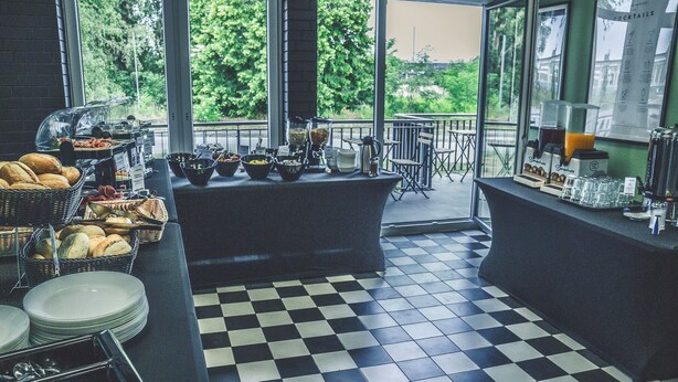 A breakfast buffet area with various food items and a checkered floor. - NEOHOSTEL Berlin (Berlin)