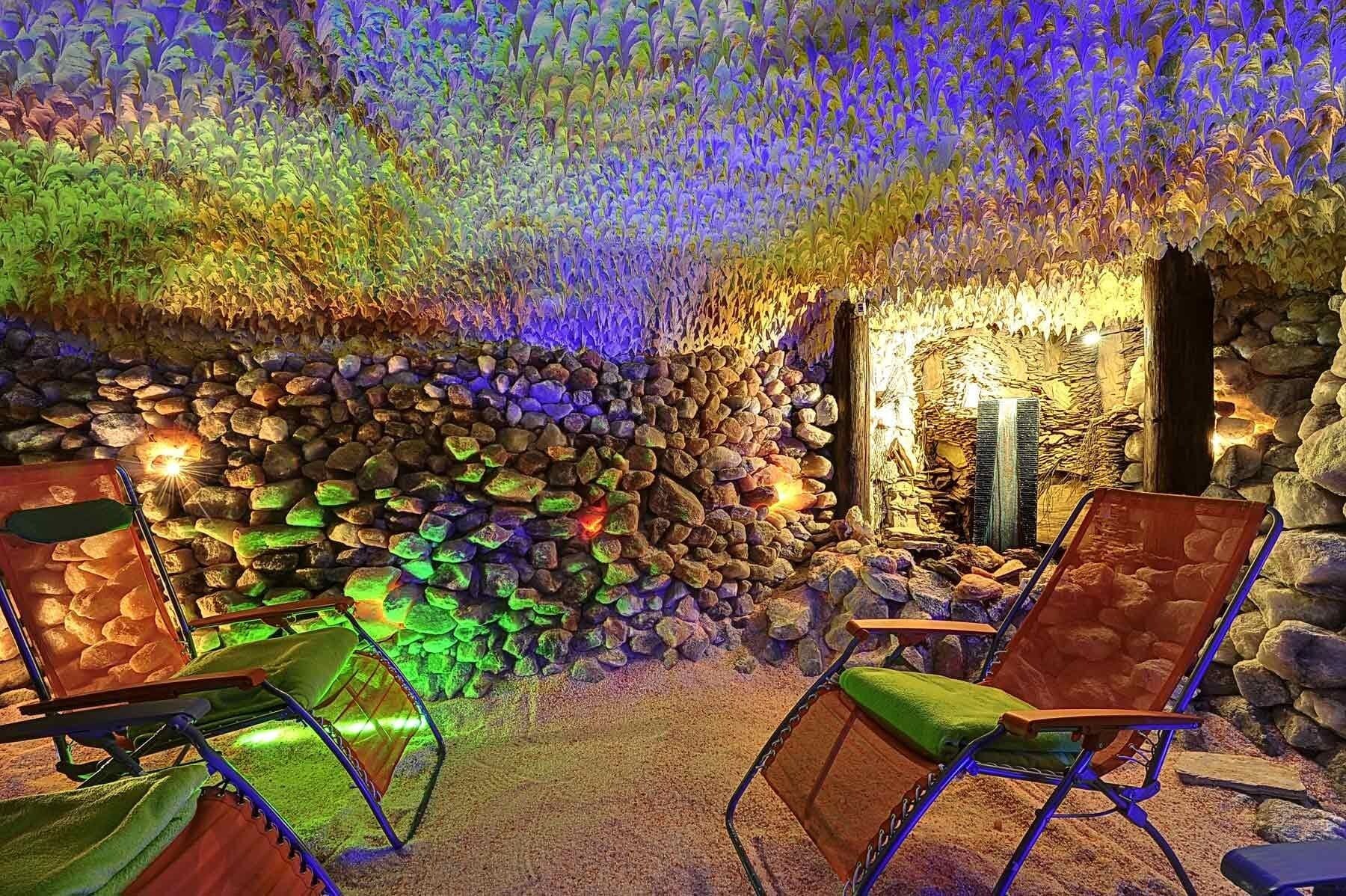Un interior con pared de piedra, una cascada y dos sillas.