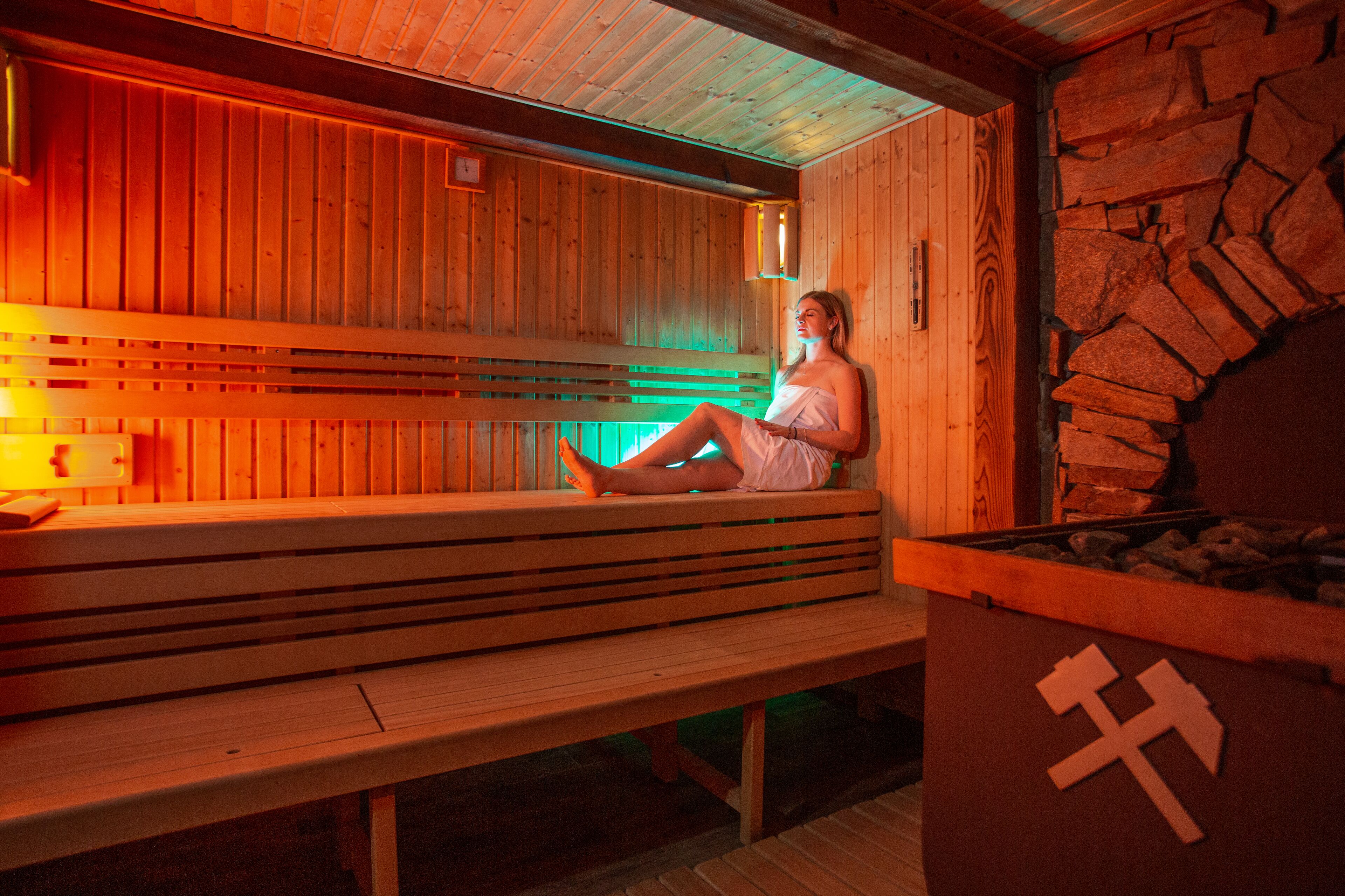 Un sauna en bois avec des bancs et un mur en pierre.