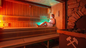 Un sauna en bois avec des bancs et un mur en pierre.