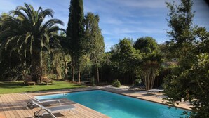 Une piscine rectangulaire dotée d’une terrasse en bois et de chaises longues.