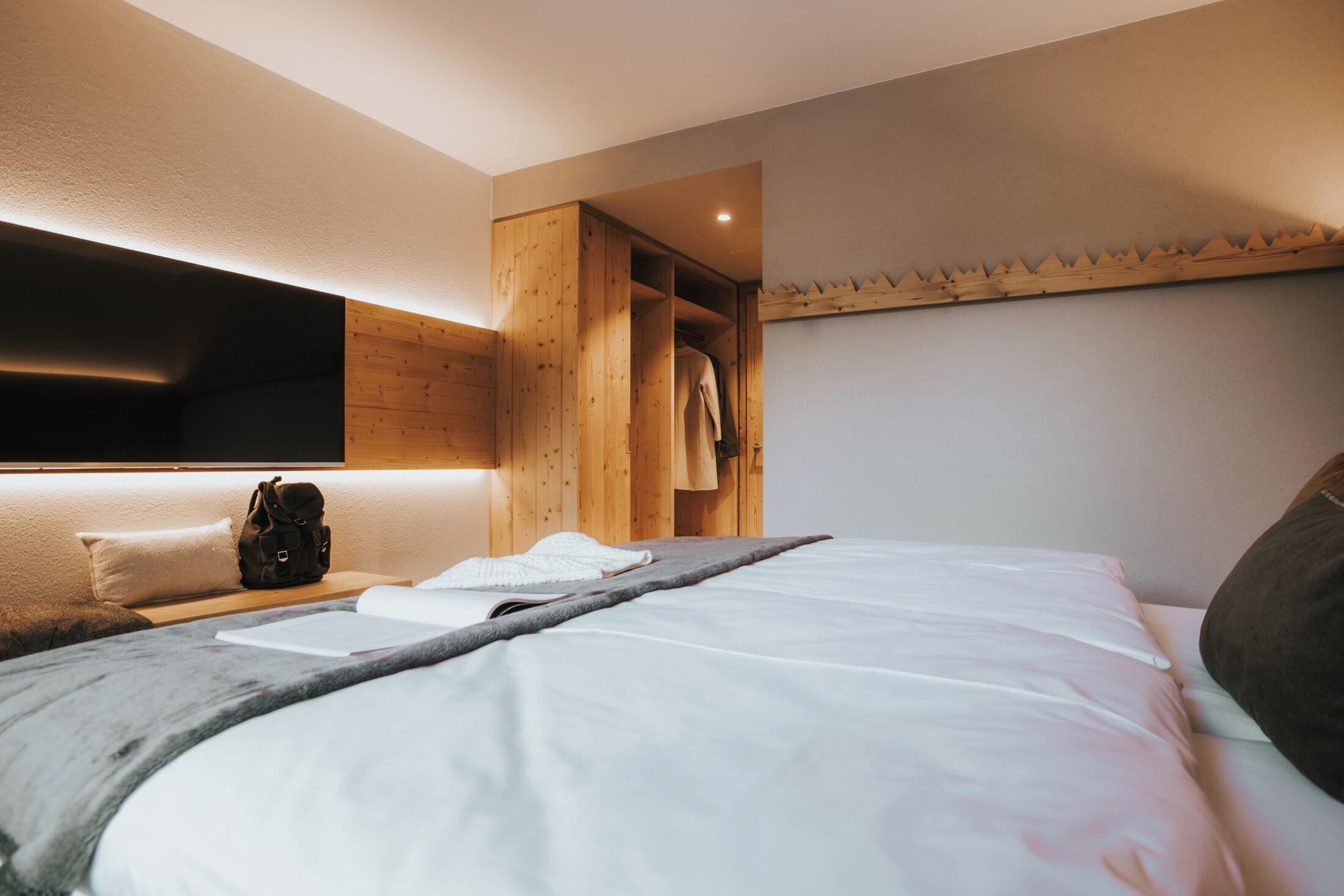 Une chambre à coucher moderne avec un grand lit, une armoire en bois et une table de chevet avec une lampe.