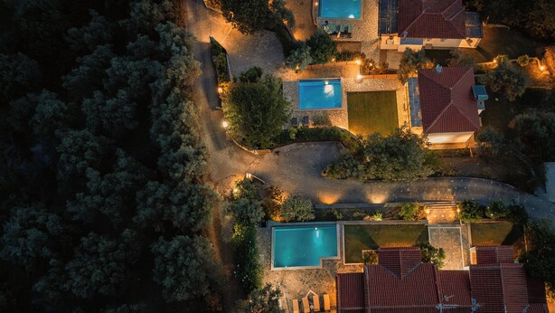 Vista aérea de un complejo turístico con varias piscinas, pasarelas interconectadas y una variedad de edificios con techos de tejas rojas.