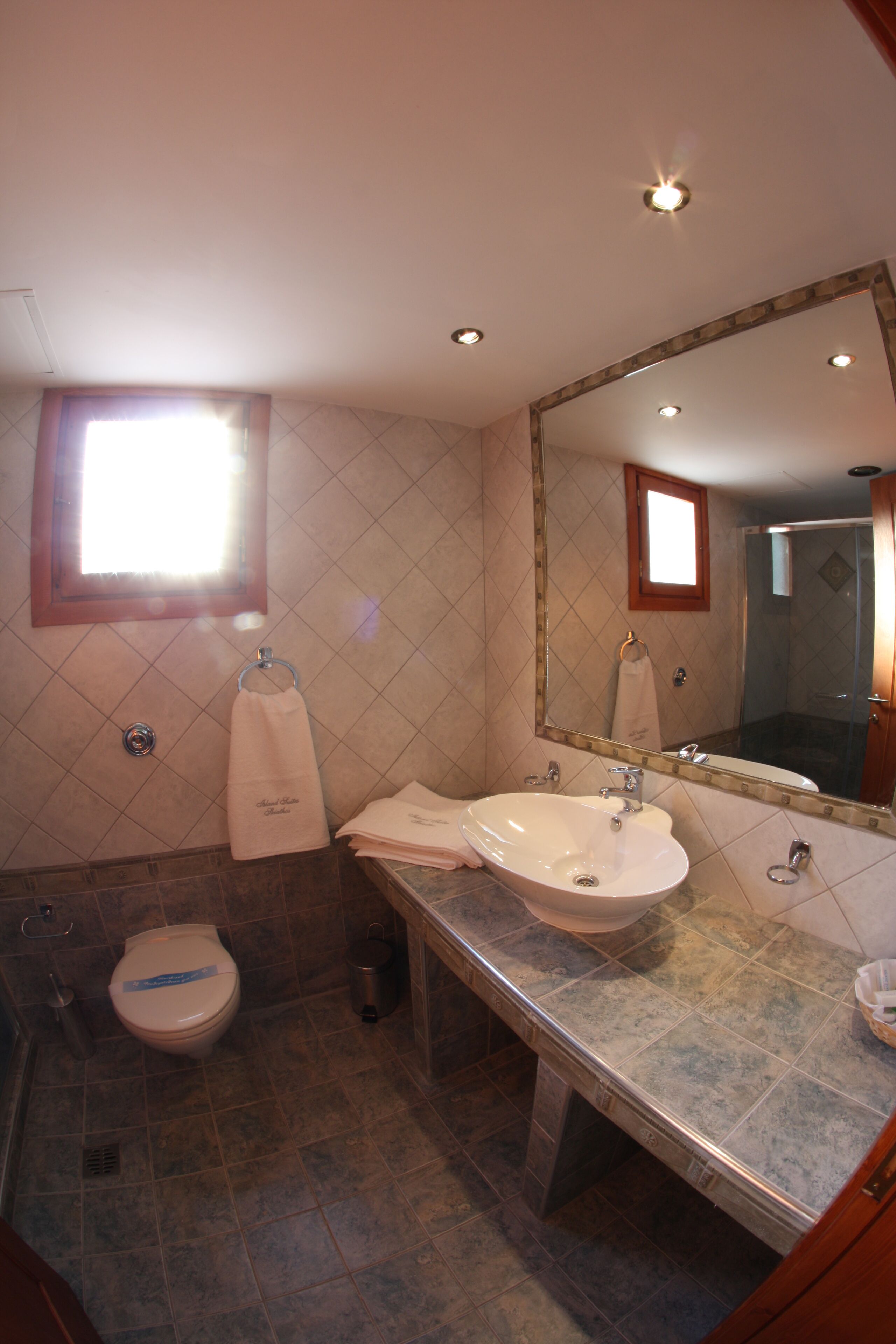 Une salle de bain avec un grand miroir, deux lavabos, des toilettes et un espace douche.