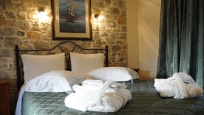 Una cama con una colcha verde acolchada, dos almohadas blancas y un cuadro con una imagen de un barco en la pared.