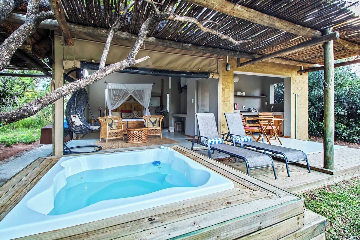 A cozy outdoor area with a hot tub, lounge chairs, and a dining set under a shaded pergola.