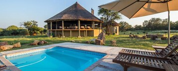 Una piscina al aire libre, sillones reclinables de piscina