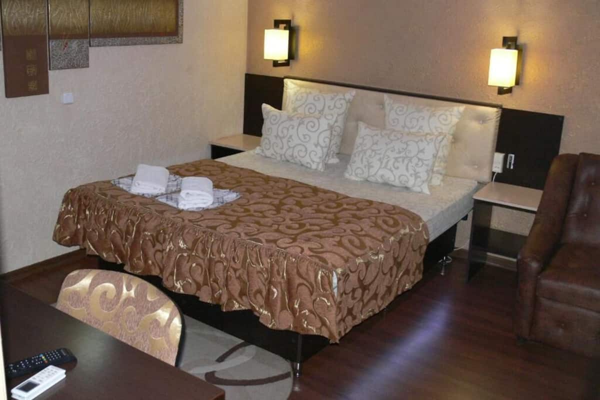 A hotel room with a bed, two bedside tables, a chair, and a desk.