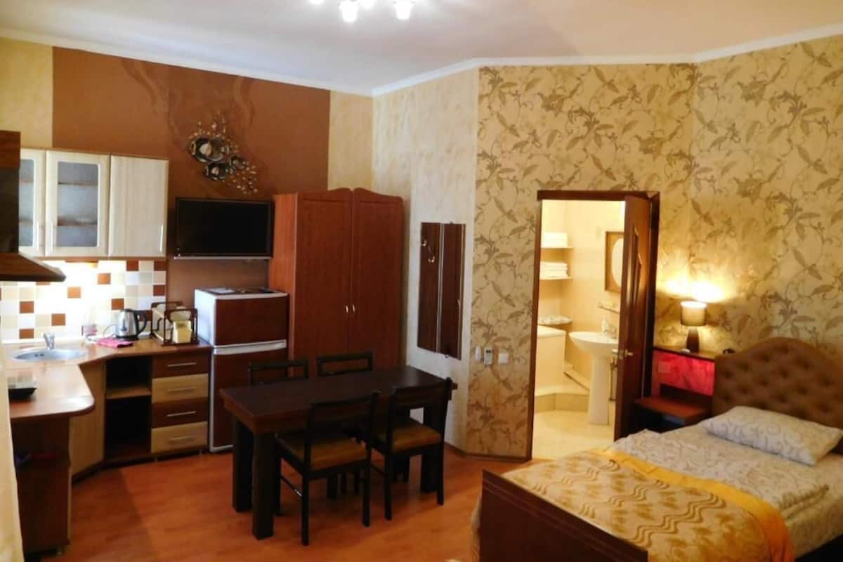 A compact room with a kitchenette, a dining area, and a bed.