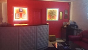 A reception area with a red wall, a tufted sofa, a coffee table, and a red couch. - Apart Hotel Dom (Odesa)