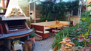 An outdoor patio with a barbecue grill, seating area, and lush greenery. - Apart Hotel Dom (Odesa)