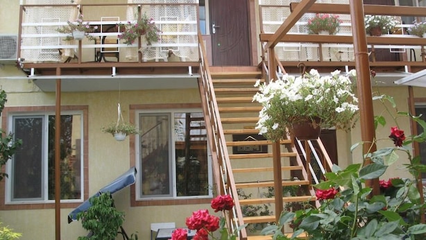 A two-story house with a wooden staircase, a balcony with lace curtains, and hanging flower baskets. - Apart Hotel Dom (Odesa)