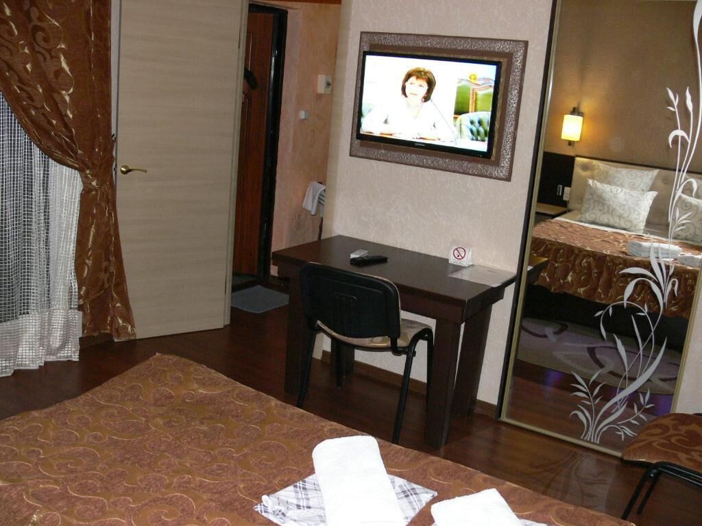A hotel room with a desk, chair, bed, and television.