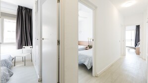 A hotel room with a bed, a chair, a desk, and a window with curtains.