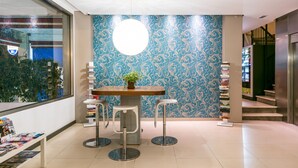 A modern interior with a round table, two bar stools, a potted plant, and a bookshelf. - Flats Friends Atlantida Corner Studio (Benidorm)