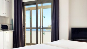 A hotel room with a bed, a TV, a microwave, and a sliding glass door to the balcony. - Flats Friends Atlantida Corner Studio (Benidorm)