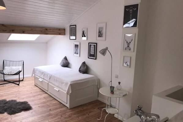 A bedroom with a bed, a chair, a small table, and wall art.