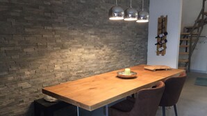 A wooden dining table with a candle, two chairs, and a brick wall. - Villetta near Argegno Dizzasco (Muronico)