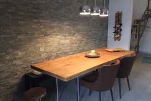 Una mesa de madera para comer con una vela, dos sillas y una pared de ladrillo.