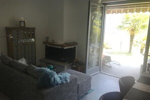 A living room with a sofa, a television, a cabinet, and a sliding glass door leading to an outdoor area.