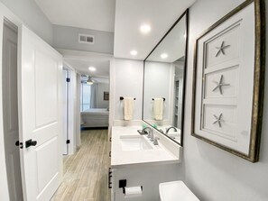 A modern bathroom with a large mirror, two sinks, and a toilet.