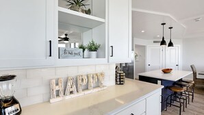 Una cucina moderna con mobili bianchi, un'isola centrale e un cartello con la scritta 'Happy New Year'.