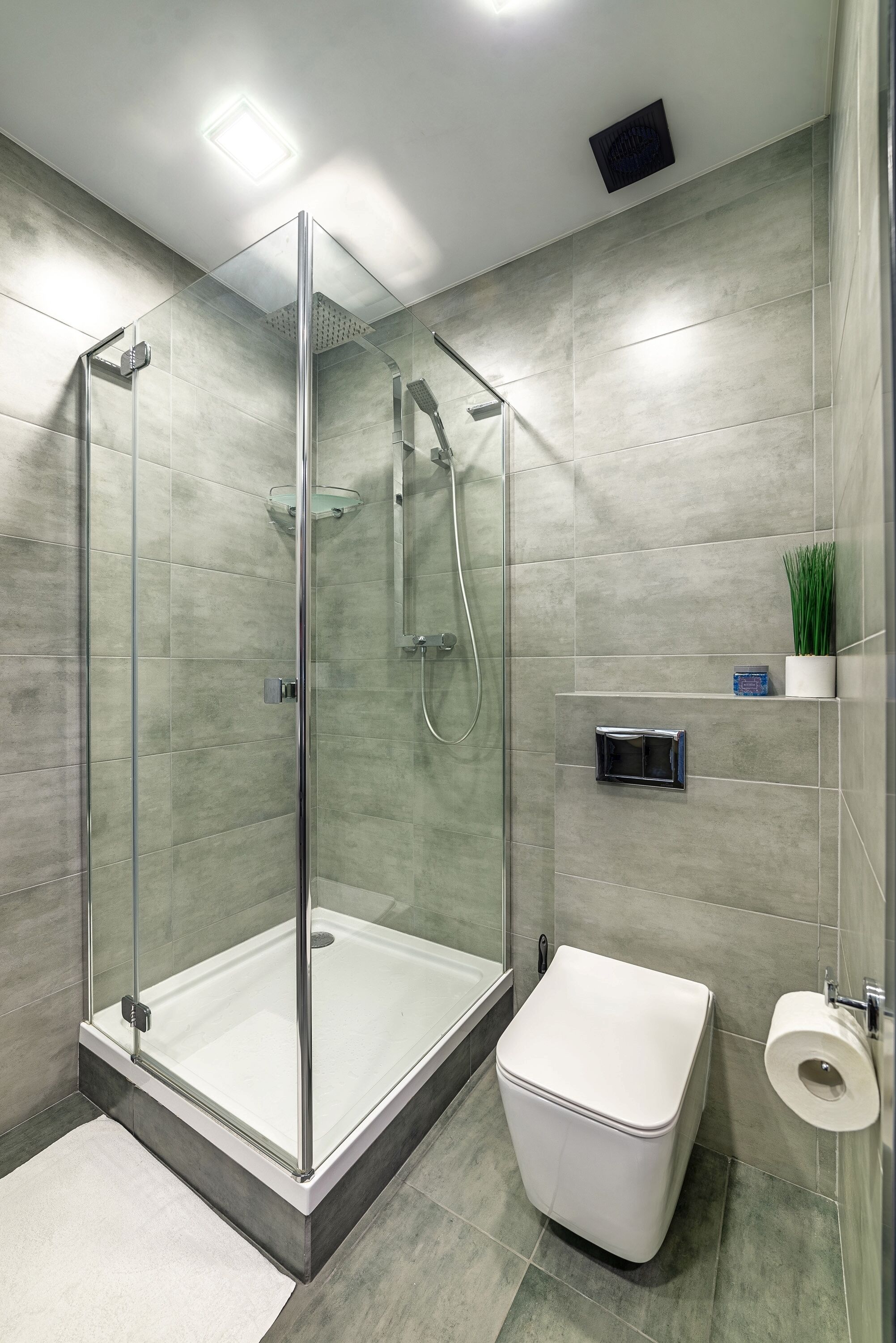 Un baño moderno con ducha de mampara de vidrio, inodoro blanco y un perchero para toallas.